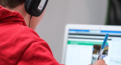 Kind mit Kopfhörern vor Laptop