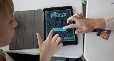 Zwei Schüler tippen gemeinsam auf den "Spielen" Button im Startmenü des Games