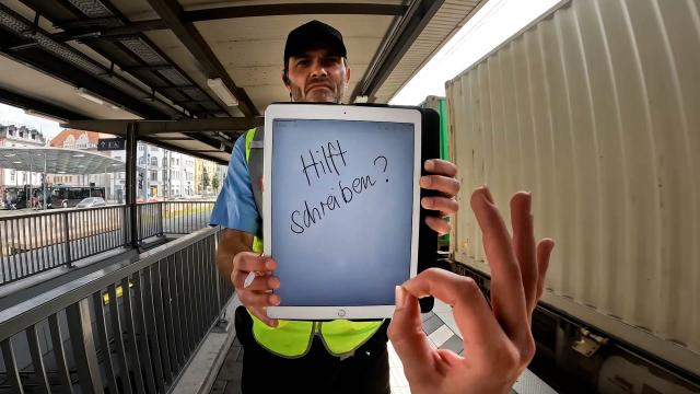 POV image of a deaf person trying to communicate with a tablet on the train station.